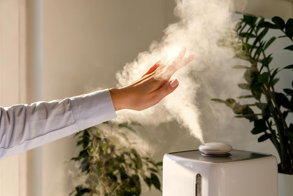 Hand touching steam from humidifier