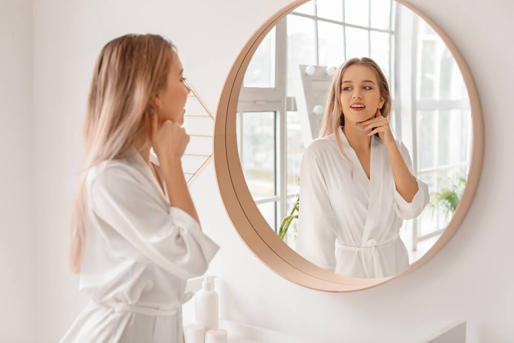 Woman looking in mirror thinking of new year's resolutions for your skin