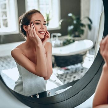 Woman looking at skin in mirror
