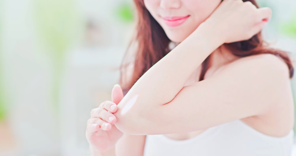Woman applying SPF to dry elbow skin