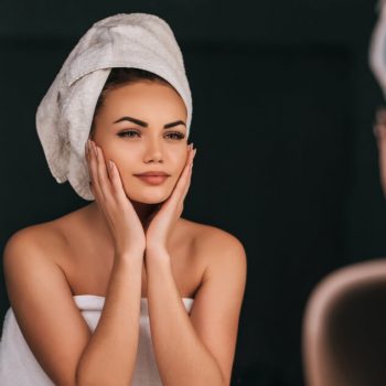 Woman looking at skin in mirror making new year's resolutions for your skin