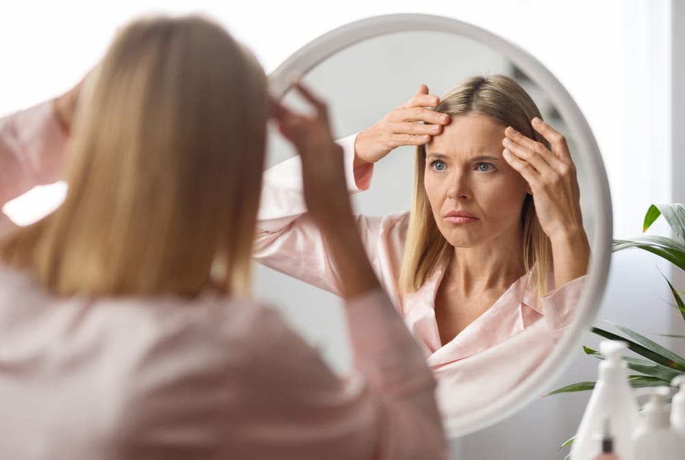Woman touching stress wrinkles on her forehead